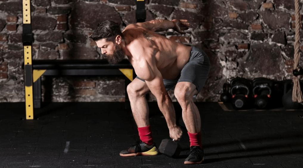 An athlete mid-dumbbell snatch movement