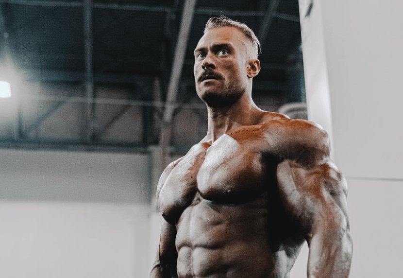 Chris Bumstead flexing and posing in spotlight