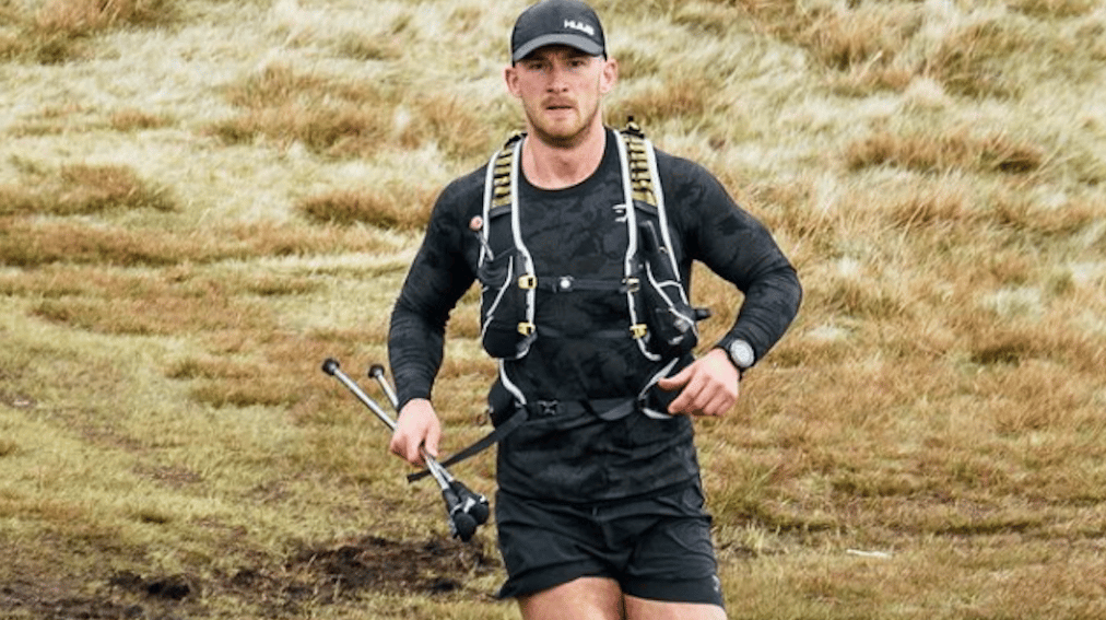 Fergus Crawley running with backpack, stick in hand