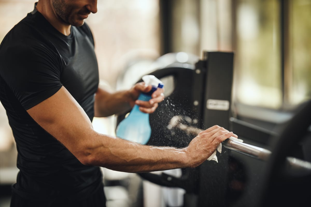 Someone spraying down a barbell for sanitation.
