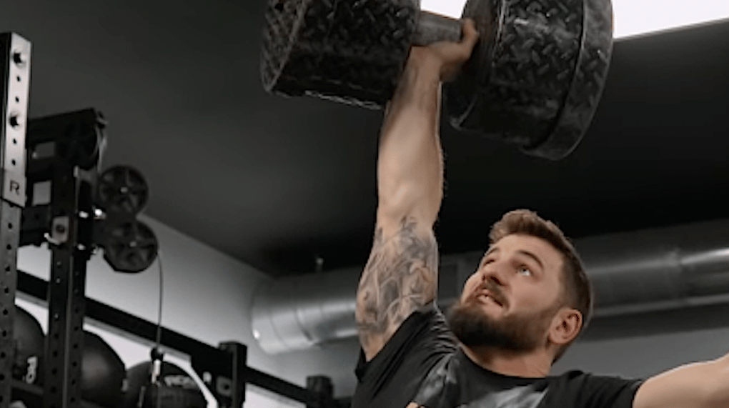 Mat Fraser completes a heavy dumbbell press July 2022