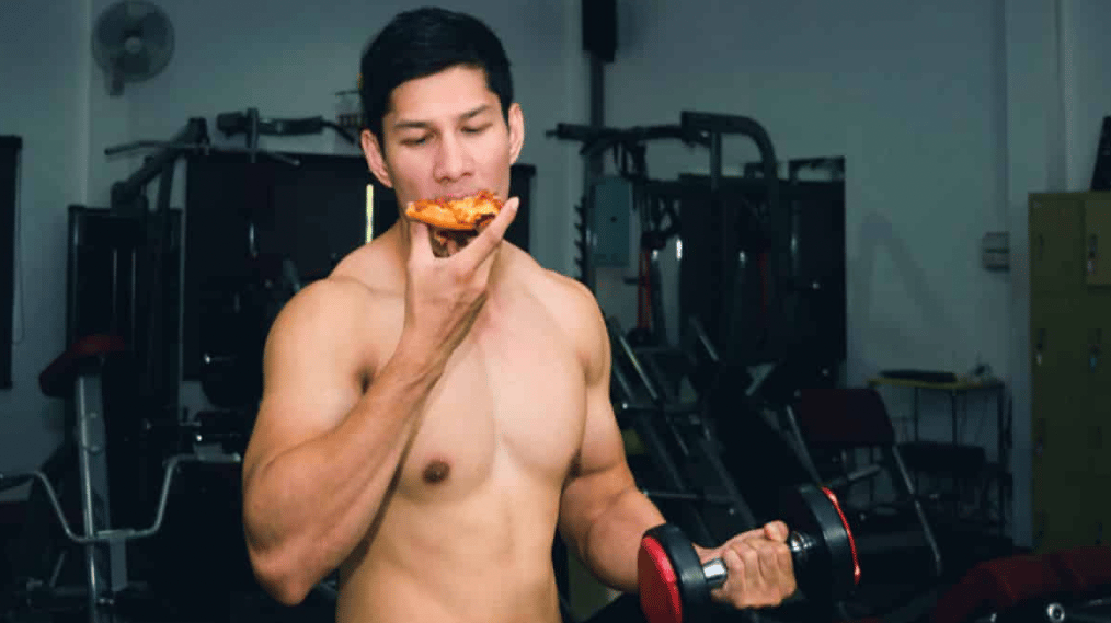 An athlete eats pizza while lifting 