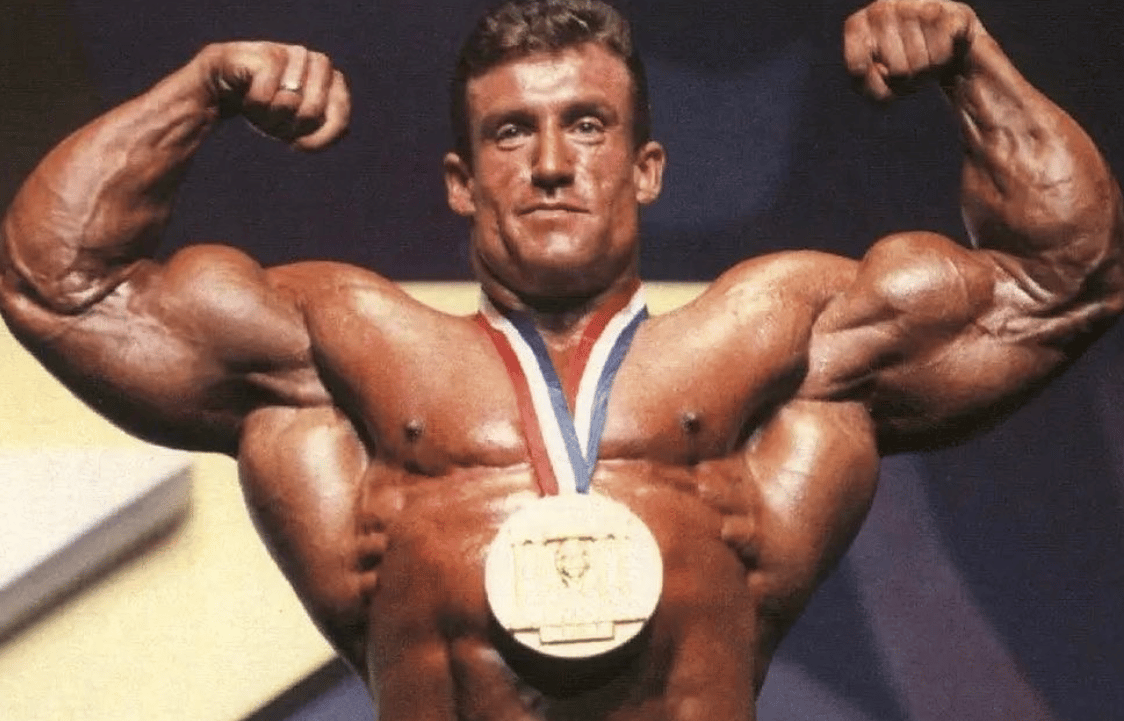Dorian Yates flexing with Olympia medal in his youth.