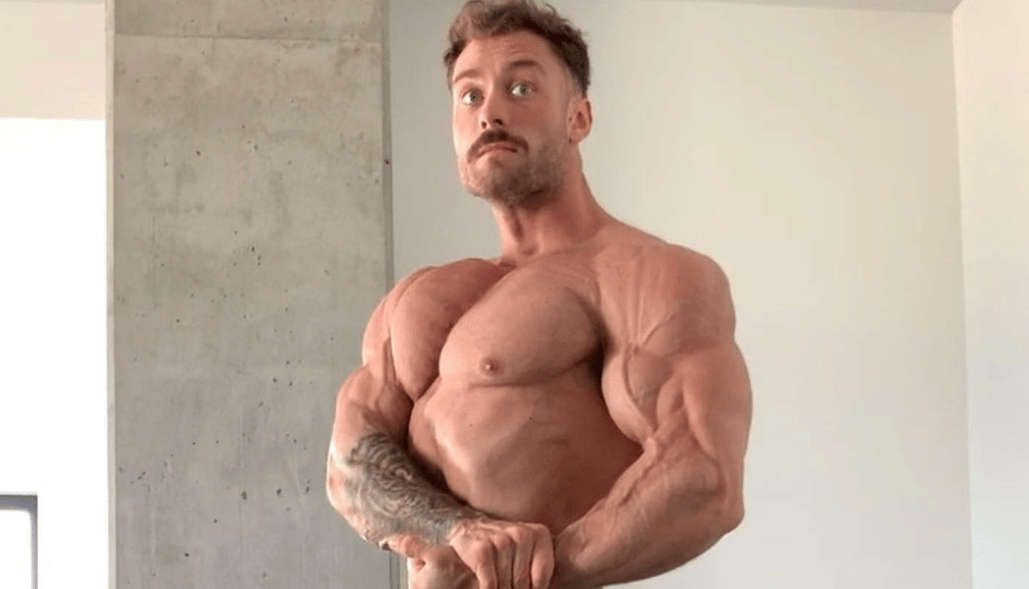 Chris Bumstead poses with his arms flexing.