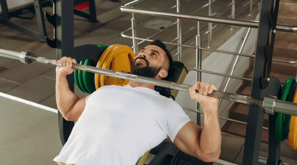 An athlete uses a barbell to bench
