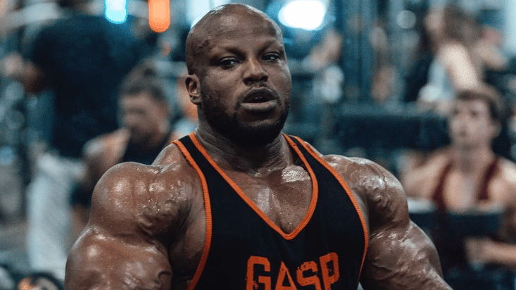 Shaun Clarida flexing arms, tank top