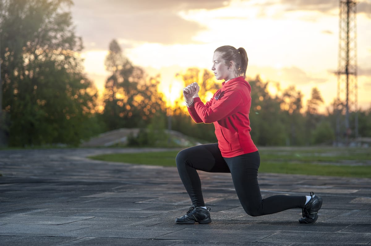 Woman split squat performance with sunset and trees in background